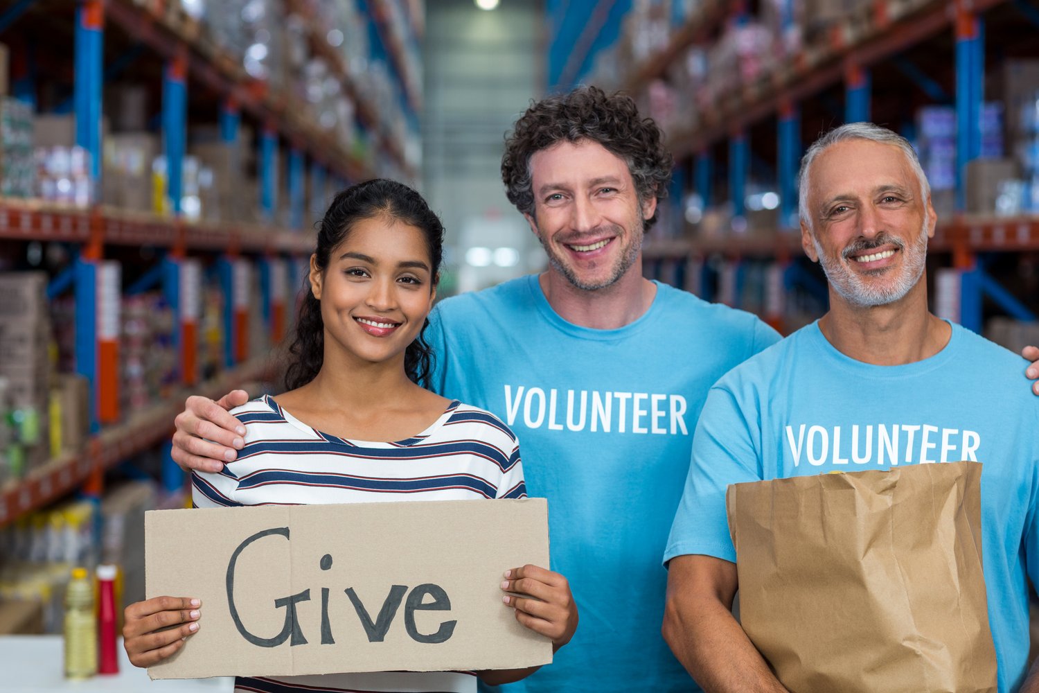 Smiling Volunteers Stand Together in Warehouse for Charity Smiling Volunteers Stand Together in Warehouse for Charity